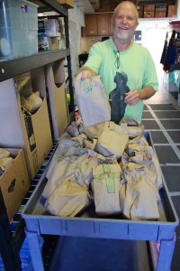 Bread of Life volunteer John Wickham loads up sack lunches that will be passed out to guests after dinner. Wickham has volunteered at the rescue mission for 12 years and said financial 