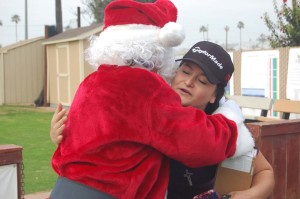 Santa, aka Tony Perez, presents Spc. Rocio Ruiz with her equipment and gets a hug in return.  Photo by Bianca Kaplanek