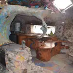 The cave-like interior of the Hippadome, where the Kahns lived, is at once cozy and bizarre. A friend carved the exotic wood kitchen counters and cabinets, and a hot tub has been built into the living room floor. A loft was constructed over the kitchen, but the Kahns slept on the cushy “lake” also built into the living room floor. (Photo by Jerry Ondash)