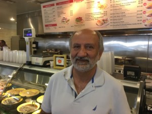 Owner Amir Movassat in front of the delicious grill section of the new Peachy’s Market & Grill. Photo David Boylan 